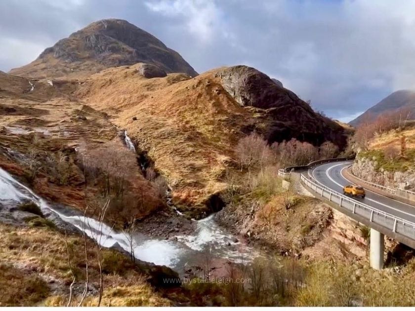 Road through Glencoe Scottish Highlands with waterfall and mountains