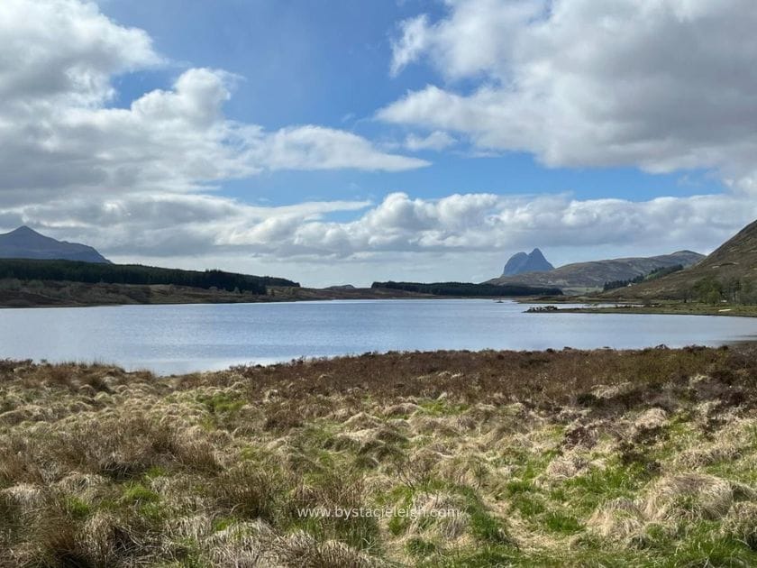 Loch in Sutherland Scottish Highlands with Suilven mountain on horizon moorland grass foreground open sky